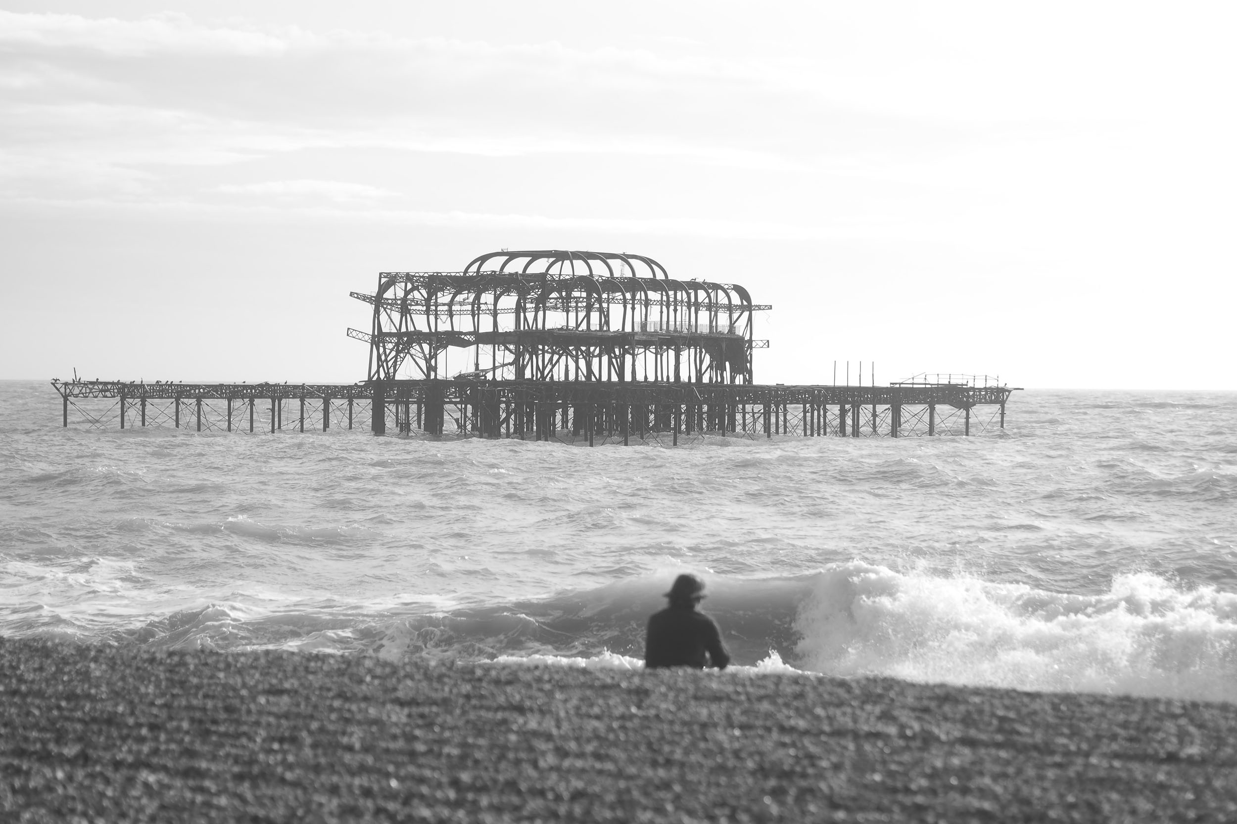 Black and White of a man on the becah by the West Pier at Brighton